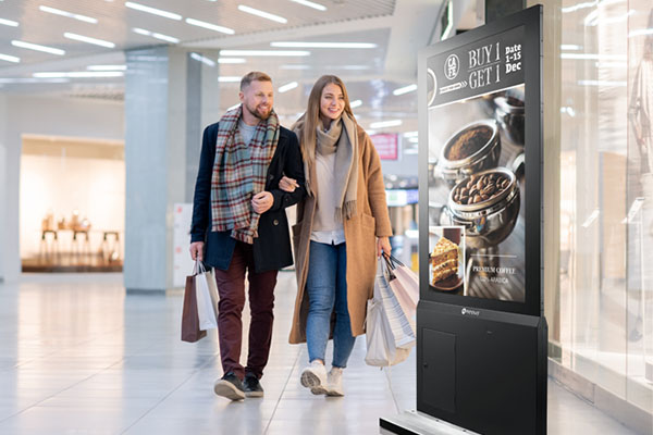 A couple is looking at AG Neovo freestanding digital kiosk display locates in the shopping mall