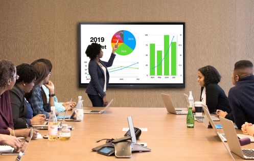 A lady is presenting in front of interactive flat panel display in the meeting room