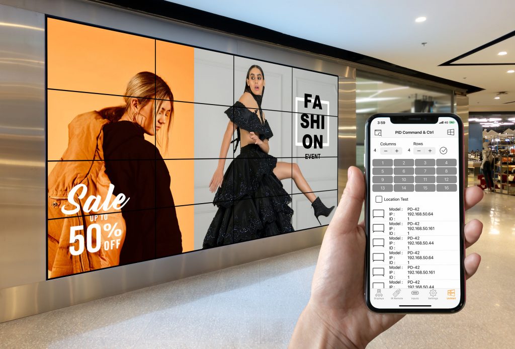 A person is using AG Neovo's PID command & control app on the mobile device to control 4 x 4 video wall displays