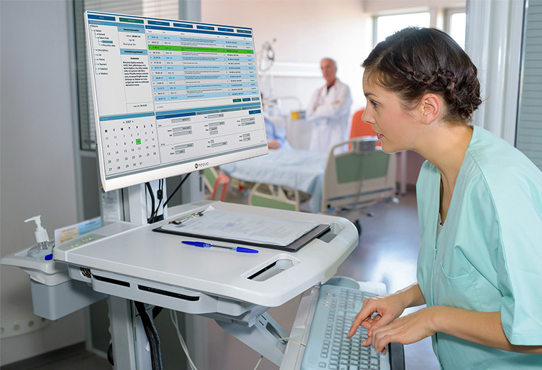 A nurse is viewing electronic health records on the clinical review monitor installed on the medical mobile cart.